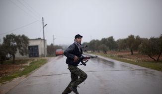 A Free Syrian Army fighter runs as Syrian government troops advance toward the town of Sarmin, in northern Syria, on Monday, Feb. 27, 2012. (AP Photo/Rodrigo Abd)