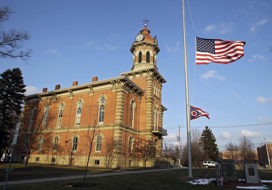 Flags fly at half-staff in front of the town hall in Chardon, Ohio, for the victims of an early-morning school shooting on Monday, Feb. 27, 2012. (AP Photo/Mark Duncan)