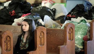 A girl attending mass at St. Francis Xavier Catholic Church sits in a pew in front of clothing and supplies that have been collected to aid victims of a tornado in Henryville, Ind., Sunday, March 4, 2012. The church was in the path of a tornado that destroyed much of the town. Three people were killed in Southern Indiana by Tornados on Friday. (AP Photo/Michael Conroy)