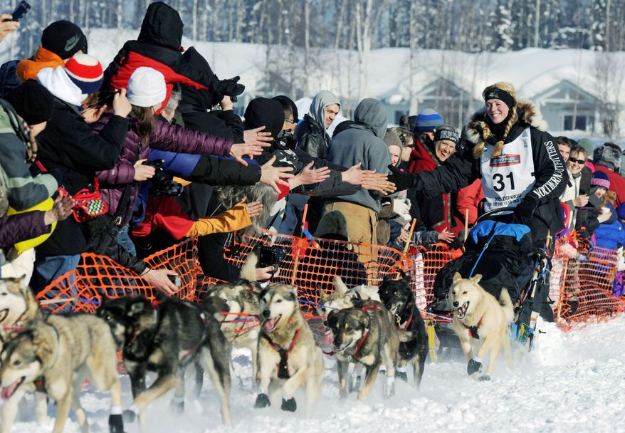 Kristy Berington acknowledges fans Sunday as she makes her way along the trail during the official start of the Iditarod Trail Sled Dog Race in Willow, Alaska. The eight-day trek offers $50,400 and a new truck to the winner. (Anchorage Daily News via Associated Press)