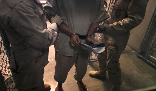 ** FILE ** A handcuffed detainee carries a workbook as he is escorted by guards after attending a &quot;life skills&quot; class in the high-security detention facility on Guantanamo Bay Naval Base in Cuba in March 2010. (AP Photo/Brennan Linsley, File)

