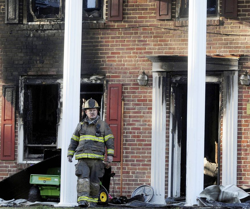A firefighter exits the front of a heavily damaged two-story home in Hope Mills, N.C., on Tuesday. A Special Forces soldier died trying to rescue his two young daughters during a fire at the house. Edward Cantrell, Isabella Cantrell, 6, and Natalia Cantrell, 4, perished in the blaze. (Associated Press)