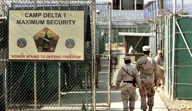 In this June 27, 2006, file photo, reviewed by the U.S. Department of Defense, U.S. military guards walk within the Camp Delta military-run prison at the Guantanamo Bay U.S. Naval Base in Cuba. (AP Photo/Brennan Linsley) ** FILE **