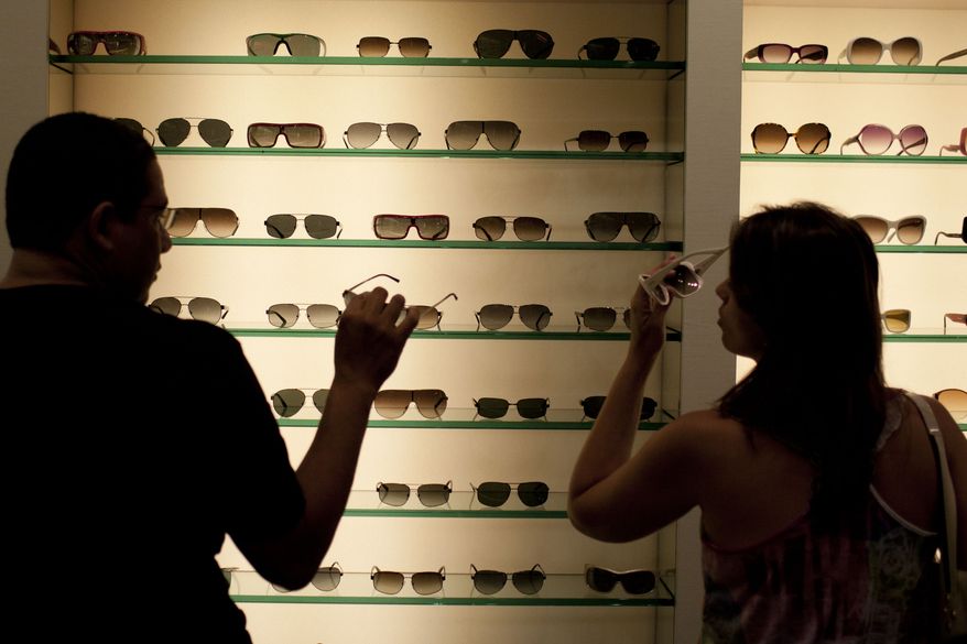 Milena Rangel (right) and her husband, Vanderson Rangel, both from Macae, Brazil, try on sunglasses in Fort Lauderdale, Fla., on Tuesday, March 6, 2012. Brazilian travelers spend more per capita than any other visitors to the United States. (AP Photo/Felipe Dana)