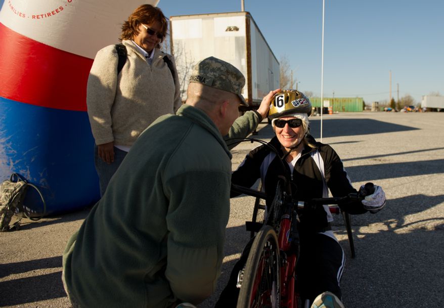 Caretaker Carrie Ruiz smiles as Sgt. 1st Class Jarrett Jongema with the Warrior Transition Command congratulates Staff Sgt. Chanda Gaeth who suffers from complications from Traumatic Brain Injury, after she completes a hand bike race with other wounded soldiers and Army veterans from across the United States in the Army Warrior Games clinics for a chance at a spot on the Army Warrior Games team, Fort Meade, Md., Sunday, March 11, 2012. The 2012 Warrior Games, held April 30th - May 5th in Colorado Springs, Colo., features representatives from Army, Navy, Air Force, Marines and Special Operations and will compete for gold metals in archery, cycling, wheelchair basketball, shooting, swimming, track and field, and sitting volleyball. (Andrew Harnik/The Washington Times)