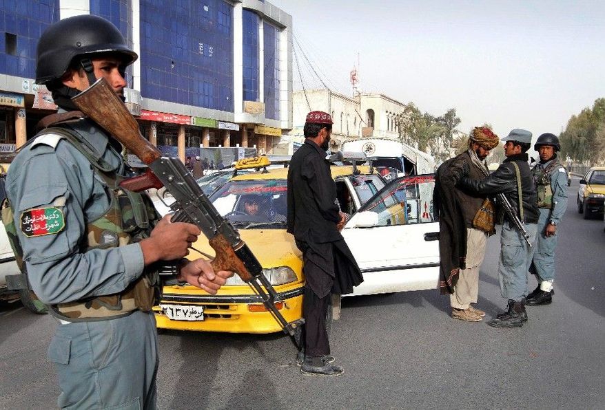 An Afghan policeman stands guard as a partner searches a taxi passenger at a police checkpoint after Sunday's killing of civilians allegedly by a U.S. soldier in Kandahar province, south of Kabul. An Afghan youth recounted Monday a terrifying scene in his home as a lone gunman moved stealthily through it on a killing spree. (Associated Press)