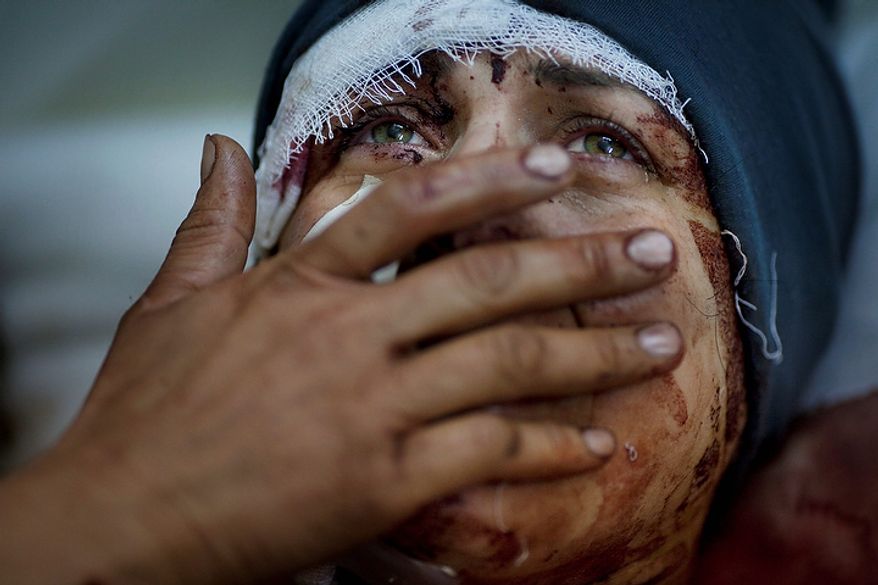 In this photo from March 10, 2012, Aida cries as she recovers from severe injuries after the Syrian Army shelled her house in Idlib north Syria. Aida's husband and and two children were killed after their home was shelled. (Associated Press)