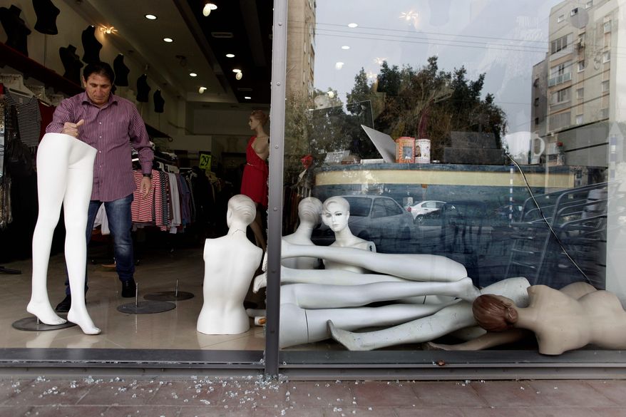 Bary Mike, an Israeli store owner, cleans up after a rocket fired from the Gaza Strip by Palestinian militants landed nearby in the port city of Ashdod on Tuesday. Israel halted its airstrikes against Gaza Strip militants early Tuesday and rocket fire from the Palestinian territory ebbed as a cease-fire ending four days of clashes started to take effect. (Associated Press)