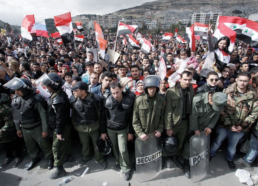 Syrian riot police stand guard during a rally Thursday supporting President Bashar Assad in Damascus. Thousands poured into the streets of the Syrian capital in a show of support for the Assad regime as soldiers tightened their siege in opposition areas on the one-year anniversary of the country's uprising. (Associated Press)
