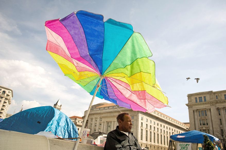 As temperatures reached an unusual high, Washington, D.C. native James Fisher, 70, seeks shelter from the sun behind a colorful umbrella at the Occupy DC encampment he has called home since October of 2011 at Freedom Plaza in Washington, D.C., Thursday, March 15, 2012. (Rod Lamkey Jr./The Washington Times)