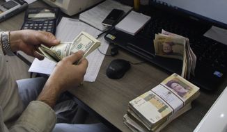 ** FILE ** A currency exchange bureau worker counts U.S. dollars, as Iranian bank notes are seen at right with portrait of late revolutionary founder Ayatollah Khomeini, in downtown Tehran, Iran, in this Wednesday, Dec. 21, 2011, file photo. (AP Photo/Vahid Salemi, file)

