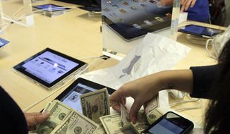 People purchase the new iPad at Apple&#39;s flagship store in New York on March 16, 2012. Apple&#39;s latest iPad drew die-hard fans to stores in the U.S. and nine other countries, many of whom lined up for hours to be among the first to buy one. (Associated Press)