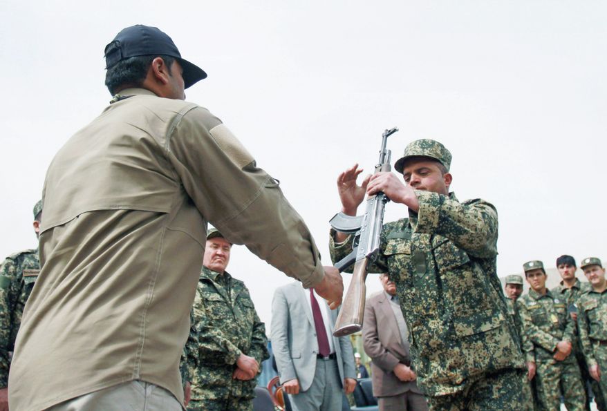 ASSOCIATED PRESS
A former private security guard (left) hands over his weapon to Jamal Abdul Naser Sidiqi, head of the Afghan Public Protection Force, during a transition ceremony Thursday of private security forces to Afghan Public Protection Force on the outskirts of Kabul. The Afghan government is giving companies extensions ranging from a few weeks to 90 days.