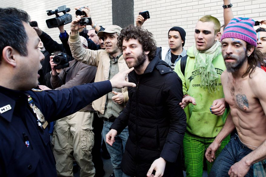 An Occupy Wall Street demonstrator is directed to step back from the scene of an arrest Saturday in New York by a police officer, after a march marking six months since the movement's founding. Protesters lack consensus on what the group's focus should be going forward. (Associated Press)