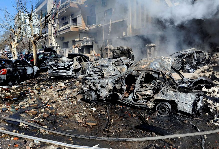 Destroyed cars on Sunday litter the area near the Syrian aviation intelligence department in Damascus. Bombs struck government targets in the Syrian capital early Saturday, killing security forces and civilians and leaving pools of blood and carnage in the streets, according to state-run television. (Associated Press)