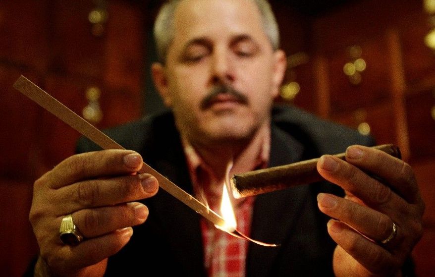 Reinaldo Ruiz lights up in one of Havana's most popular cigar rooms, at the Conde de Villanueva hotel, and a woman indulges at the annual cigar festival in the Cuban capital. Many state-owned restaurants, however, have quietly gone smoke-free in recent weeks. (Associated Press)