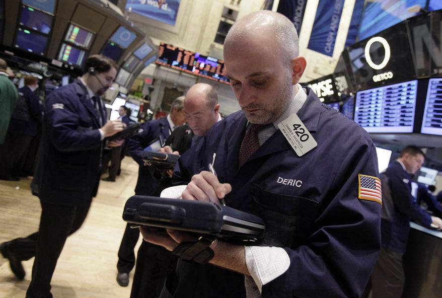 Damian Bagarozza (right) works with fellow traders on the floor of the New York Stock Exchange on Monday, March 19, 2012, in New York. (AP Photo/Richard Drew)