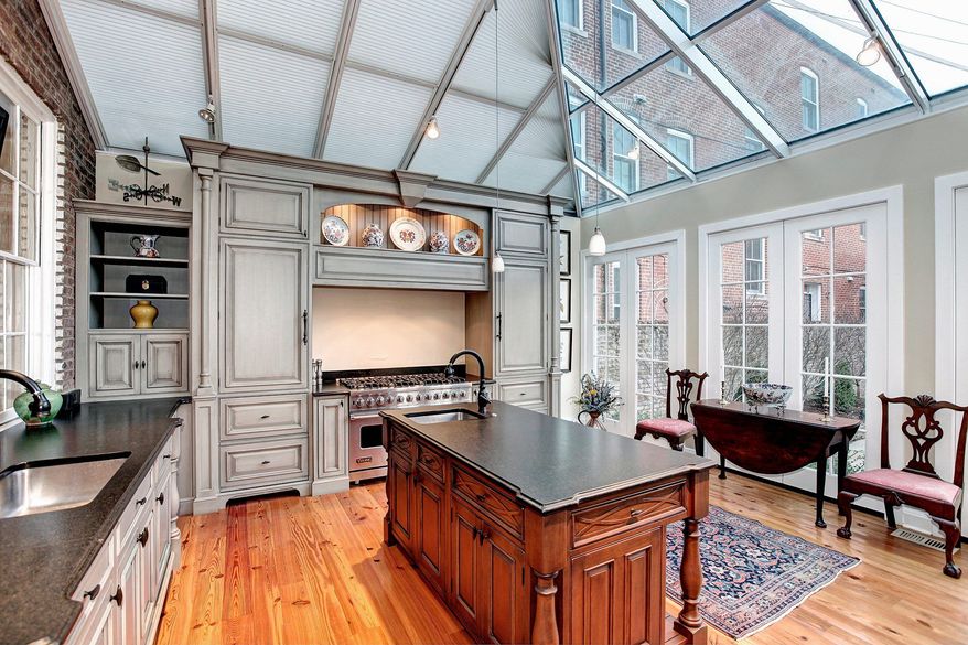 The gourmet kitchen of the town home at 3265 N St. NW in Georgetown has a glass ceiling, an exposed-brick wall, custom-designed cabinets, granite counters and a center island.