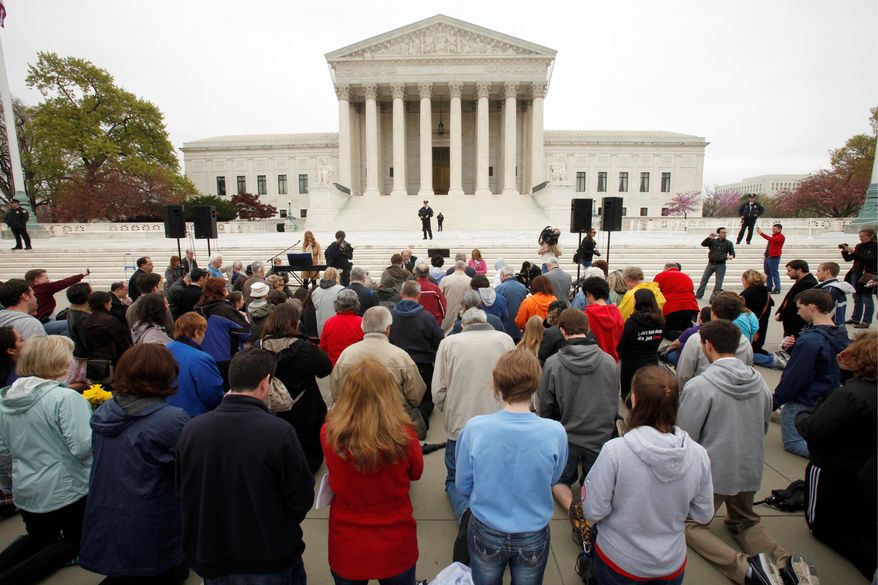 Members of Christian faith organizations kneel in prayer in front of the Supreme Court in Washington on Sunday as part of "Encircle the Court in Prayer" on the eve of the Supreme Court arguments on President Obama's health care legislation. (Associated Press)