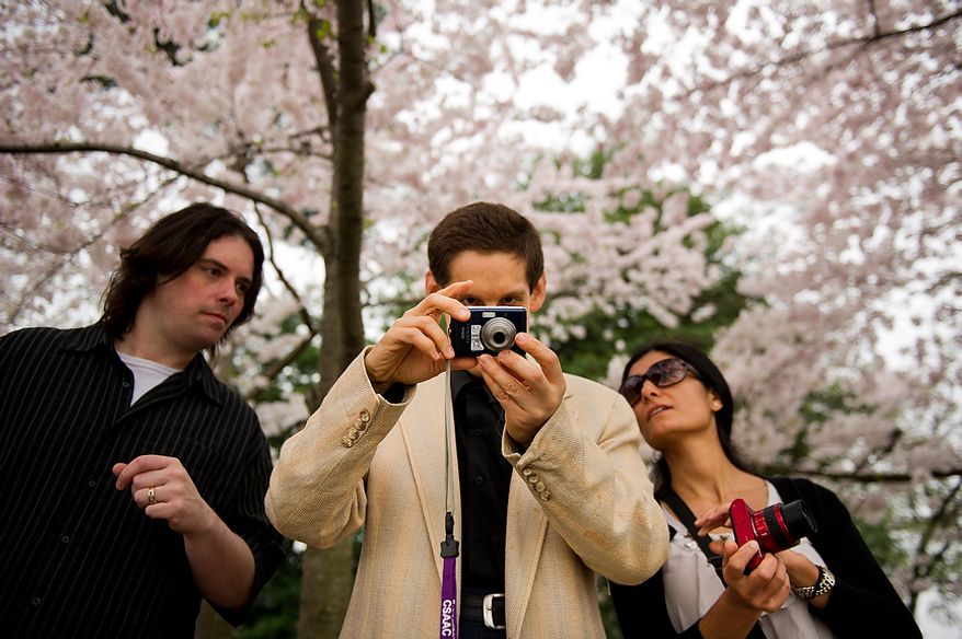 Autistic adult James L., center, with Community Services for Autistic Adults and Children, based in Montgomery Village, Md., is accompanied by staff members Craig Pardini, left, and Dide Cimen, right, as he takes photographs of the Cherry Blossoms along the Tidal Basin, Washington, D.C., Wednesday, March 21, 2012. The “InFocus Project†is a way for adults with autism to develop forms of self expression and social skills while producing work that has been featured in art shows, given to donors to C.S.A.A.C., and sold on an online store. (Andrew Harnik/The Washington Times)