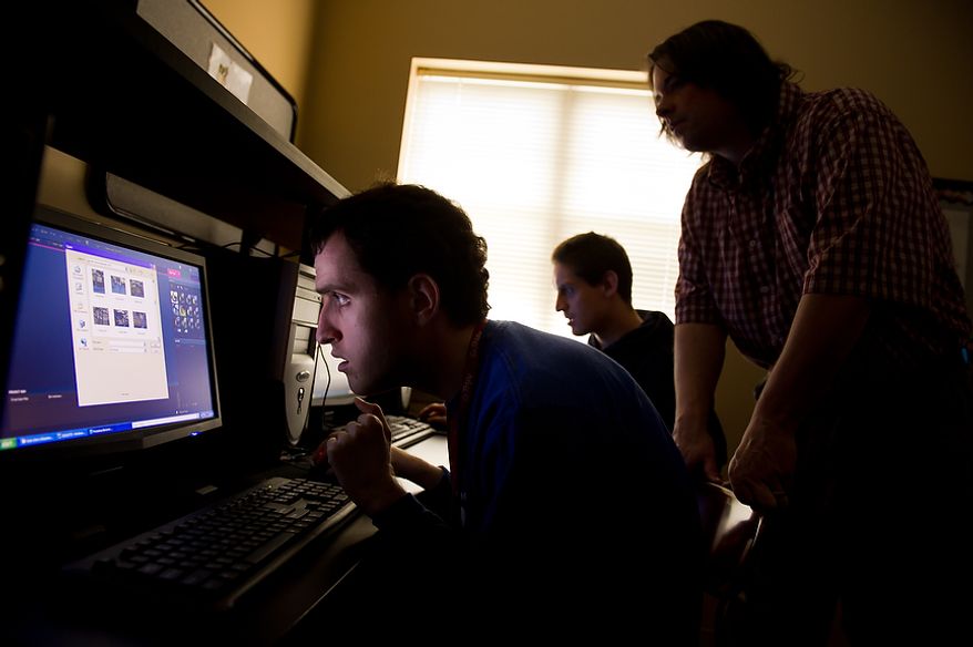 Autistic adults Brian D., left, and James L., second from left, edit their photographs of the Cherry Blossoms taken along the Tidal Basin with the help of staff member Craig Pardini, right, at a computer lab at the Community Services for Autistic Adults and Children, Montgomery Village, Md., Thursday, March 22, 2012. The two are a part of the “InFocus Project†which helps adults with autism to develop forms of self expression and social skills while producing work that has been featured in art shows, given to donors to C.S.A.A.C., and sold on an online store. (Andrew Harnik/The Washington Times)
