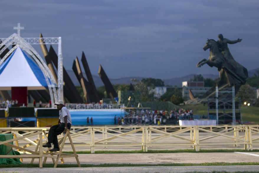 A man sits on a fence at Antonio Maceo Revolution Square on Sunday, March 25, 2012, in Santiago, Cuba. Pope Benedict XVI, who arrives in the city on Monday, will celebrate Mass on the square. (AP Photo/Esteban Felix)