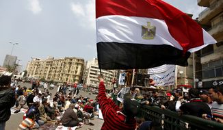An Egyptian protester waves the national flag March 23, 2012, as others attend the Friday noon prayer in Cairo&#x27;s Tahrir Square. (Associated Press)