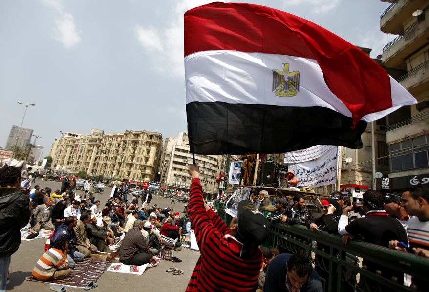 An Egyptian protester waves the national flag March 23, 2012, as others attend the Friday noon prayer in Cairo's Tahrir Square. (Associated Press)