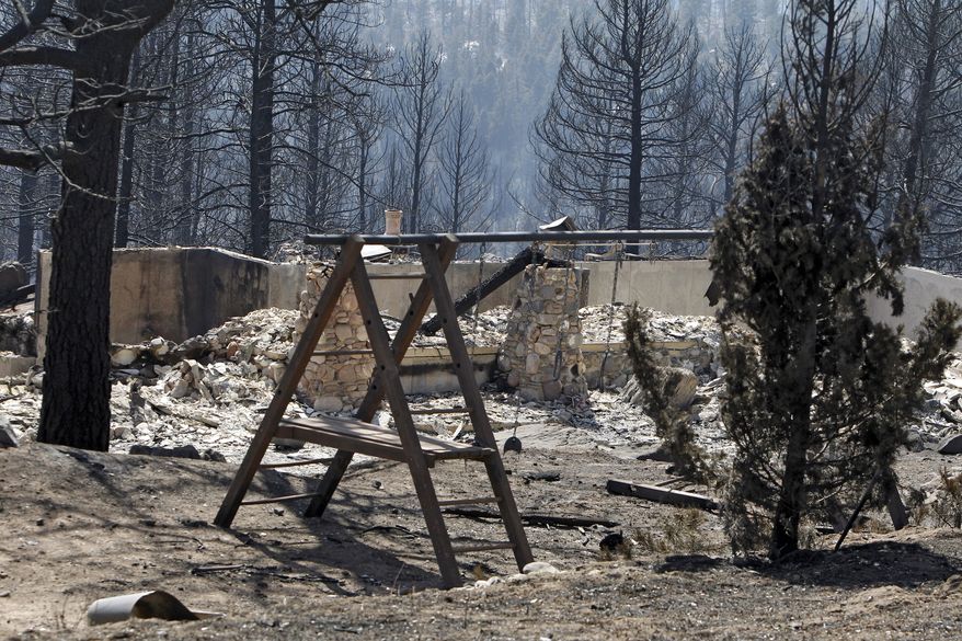 The ruins of a home destroyed by a wildfire are framed by a child's swing set near Conifer, Colo., on March 28, 2012. Two people died in the wildfire that started two days earlier. (Associated Press)