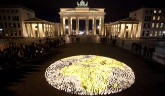About 5000 candles arrange to a globe lights in front of the Brandenburg Gate prior to the landmark switched off the lights to mark &quot;Earth Hour&quot; in Berlin, Saturday, March 31, 2012. (AP Photo/Markus Schreiber)