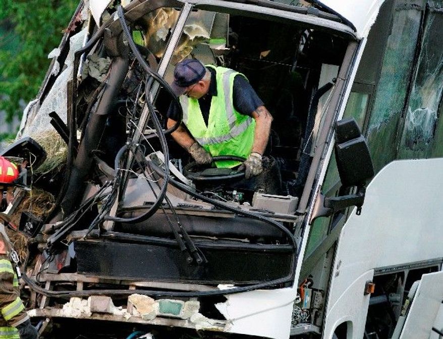 An emergency worker wrestles with the steering wheel on a wrecked bus in which 17 passengers headed for a retreat in Missouri died Aug. 8, 2008, in Sherman, Texas. The bus had been inspected at a state-certified station, an operation that many safety advocates believe receives lax federal oversight. (Associated Press)