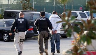 **FILE** Immigration and Customs Enforcement (ICE) agents take a suspect into custody as part of a nationwide immigration sweep in Chula Vista, Calif., on March 30, 2012. (Associated Press)