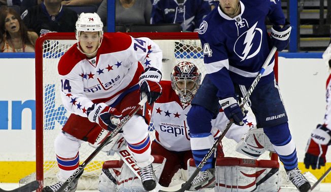 Washington Capitals goalie Michal Neuvirth, center, of the Czech Republic, looks for a shot between teammate John Carlson, left, and Tampa Bay Lightning&#x27;s Brett Connolly during the first period of an NHL hockey game Monday, April 2, 2012, in Tampa, Fla. (AP Photo/Mike Carlson)