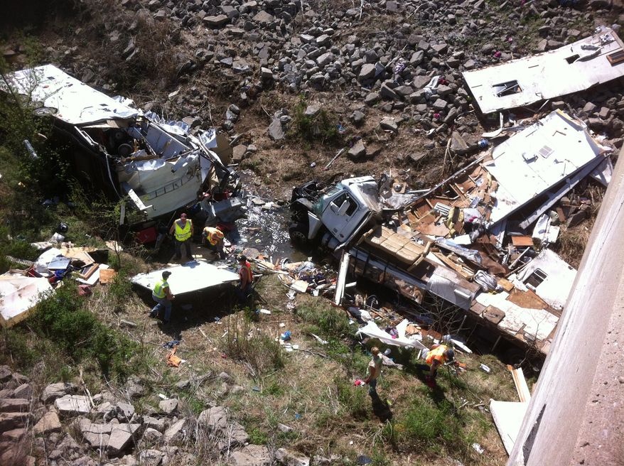 Officials work the scene of a Minnesota-bound motor home on April 1, 2012, in a ravine off Interstate 35 in northeast Kansas. The Kansas Highway Patrol said the northbound Freightliner motor home was carrying 18 people and pulling a trailer when the driver lost control at 9 a.m. that morning and crashed into the ravine. Five were killed. (Associated Press/KMBC-TV)