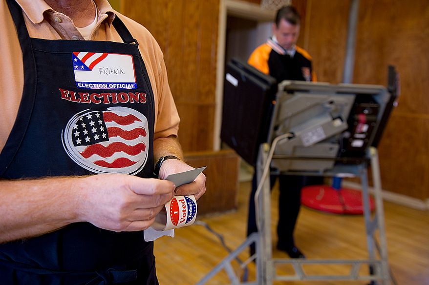 Ballot clerk Frank Gainer (left) holds "I Voted" stickers while a D.C. resident casts his ballot in the D.C. primary election at the Palisades Recreation Center on Tuesday, Feb. 3, 2012. The only real contested race in this ward was for an at-large council seat. Voter turnout was not huge, but there was a steady stream of voters coming in. (Barbara L. Salisbury/The Washington Times)