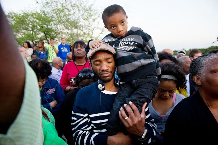 Steven Harris of Atlanta, Ga. holds his son Joyce, 6, for a moment of silence during a candle light vigil at the Martin Luther King, Jr. Memorial on the 44th Anniversary of King's assassination. (Andrew Harnik/The Washington Times)