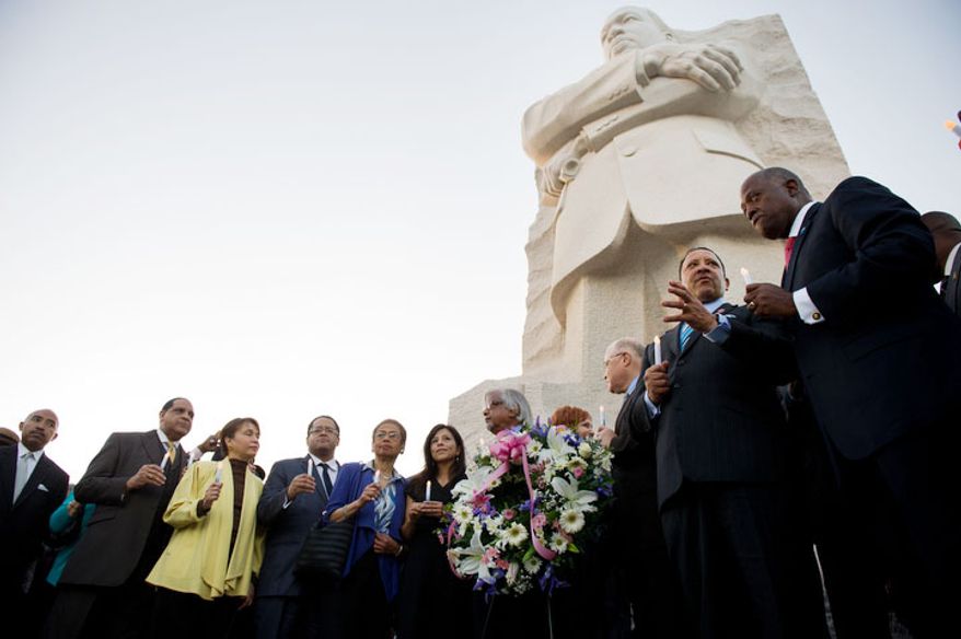 Dignitaries including Delegate Eleanor Holmes Norton (fifth from right), D.C. Democrat; Christine Chavez (sixth from right,), the granddaughter of Cesar Chavez; Arun Gandhi (fifth from right), the grandson of Mahatma Gandhi; Harry Johnson (right), president and CEO of the Martin Luther King Jr. Memorial Project; and Marc Morial (second from right), president of the National Urban League, lead a candlelight vigil at the Martin Luther King Jr. Memorial. (Andrew Harnik/The Washington Times)