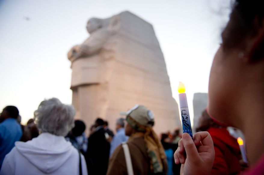 Cristina Rivera of St. Louis, Mo., right, holds an L.E.D. candle as dignitaries lead a candle light vigil at the Martin Luther King, Jr. Memorial. (Andrew Harnik/The Washington Times)