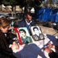 Figura Rustamova and her husband, Avaz Hasanov, show photos of Rustamova&#39;s brother, Furzoli (left), who was killed during the Khojaly Massacre, and a neighbor who was also a victim of the tragedy. (Eric J. Lyman/Special to The Washington Times)