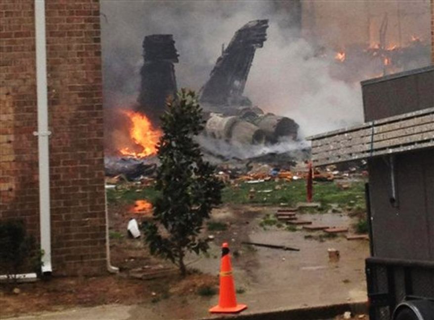 The burning fuselage of an F/A-18 Hornet lies smoldering after crashing into a residential building in Virginia Beach, Va., Friday, April 6, 2012. The Navy did not immediately return telephone messages left by The Associated Press, but media reports indicate the two aviators were able to eject from the jet before it crashed. They were being treated for injuries that were not considered life threatening. (AP Photo/Kandice Angel)