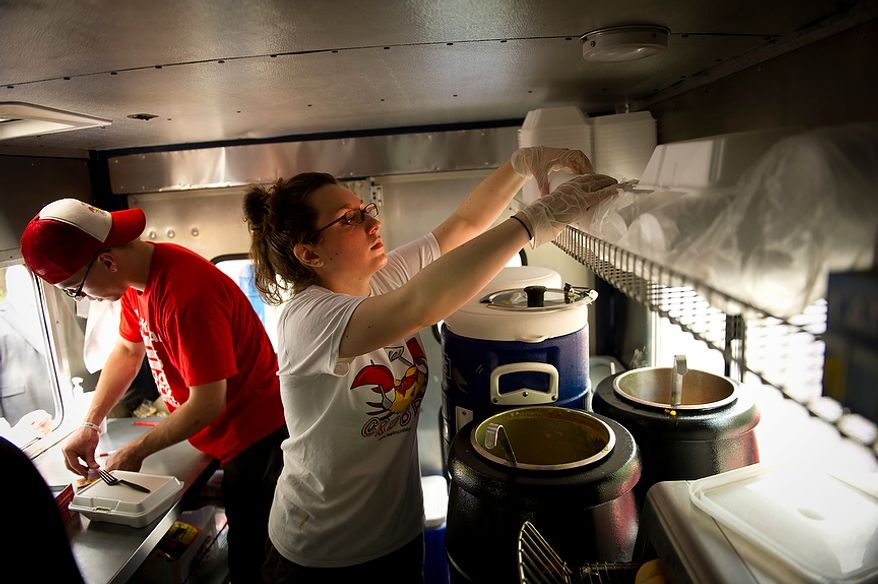 Sophia Stellabotte (right) and Feelin' Crabby? food truck owner Alex Tsamouras (left) work serving lunch in the small confines of the Feelin' Crabby? food truck, parked near the corner of Virginia Avenue 20th Street NW and in Washington, D.C., Wednesday, April 4, 2012. (Rod Lamkey Jr/The Washington Times)