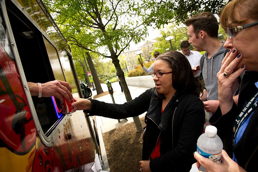 Valencia Ford (left) and Linda Neils (right) both of Washington, D.C., receive their lunches at the Feelin' Crabby? food truck, parked near the corner of Virginia Avenue 20th Street NW and in Washington, D.C., Wednesday, April 4, 2012. (Rod Lamkey Jr/The Washington Times)