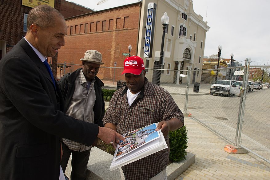 Thomas A. Hart, Jr., a local property owner, left, and Michael Hood of Washington, D.C., second from left, looks at Charles Ramsey's poster design of a newly installed stainless steel statue of D.C. native and jazz legend Duke Ellington with music legends super imposed into it while outside the redesigned historic Howard Theatre which is set to reopen with a ribbon cutting Monday and an opening night gala on Thursday, Washington, D.C., Thursday, April 5, 2012. (Andrew Harnik/The Washington Times)
