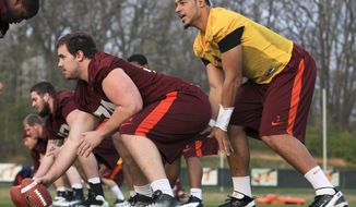 Virginia Tech quarterback Logan Thomas, right, takes a snap from center Andrew Miller, front left, during the opening day of spring NCAA college football drills on campus in Blacksburg, Va., on Wednesday, March 28, 2012. (AP Photo/The Roanoke Times, Matt Gentry)