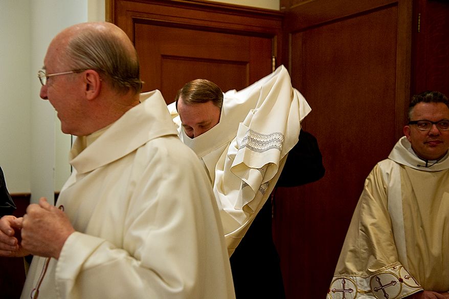 Father Mark Knestout (center), director of the office of worship for the Archdiocese of Washington, gets into his vestments for the Mass of the Lord's Supper at the Cathedral of St. Matthew the Apostle in Washington, D.C., on April 5, 2012, which was Holy Thursday. (Barbara L. Salisbury/The Washington Times)