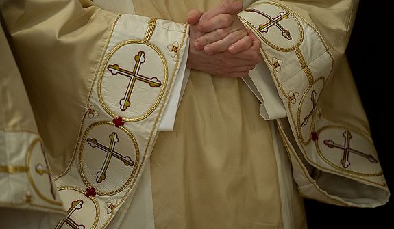 A priest wearing a chasuble, a ceremonial vestment, holds his hands in prayer as he awaits the beginning of the Mass of the Lord&#39;s Supper at the Cathedral of St. Matthew the Apostle in Washington, D.C., on April 5, 2012, which was Holy Thursday. (Barbara L. Salisbury/The Washington Times)
