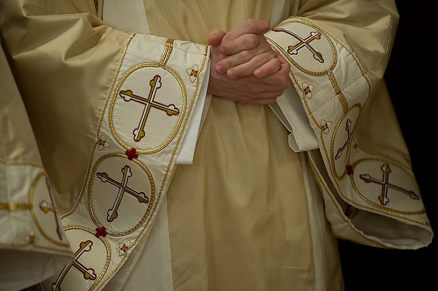 A priest wearing a chasuble, a ceremonial vestment, holds his hands in prayer as he awaits the beginning of the Mass of the Lord's Supper at the Cathedral of St. Matthew the Apostle in Washington, D.C., on April 5, 2012, which was Holy Thursday. (Barbara L. Salisbury/The Washington Times)