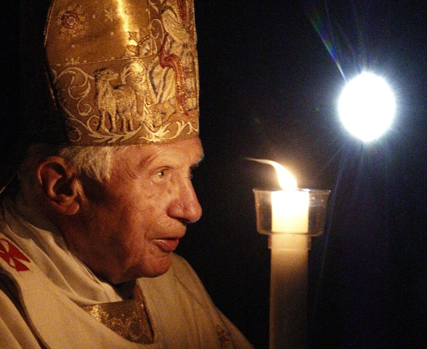 Pope Benedict XVI, holding a tall, lit, white candle, enters a hushed and darkened St. Peter's Basilica, at the Vatican Saturday, April 7, 2012, to begin the Vatican's Easter vigil service. Except for the twinkle of camera flashes, the basilica was almost pitch-black as the thousands of faithful in pews awaited Benedict's arrival Saturday night. (AP Photo/Pier Paolo Cito)