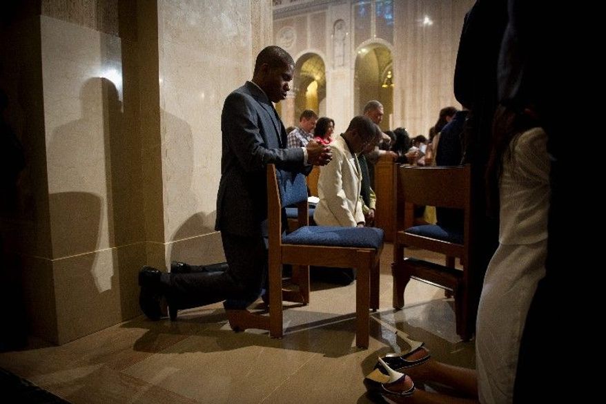 Hilary Unaegbu of Bowie kneels in prayer, during the Easter Sunday Mass at the Basilica of the National Shrine of the Immaculate Conception in Washington. (Rod Lamkey Jr./The Washington Times)