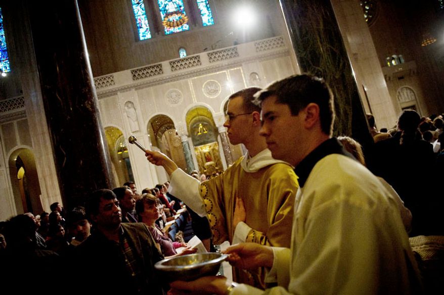 Reverend Brother Matthew Carroll blesses people with Holy Water as he walks along the aisles during the Easter Sunday Solemn Mass at the Basilica of the National Shrine of the Immaculate Conception. (Rod Lamkey Jr/The Washington Times)